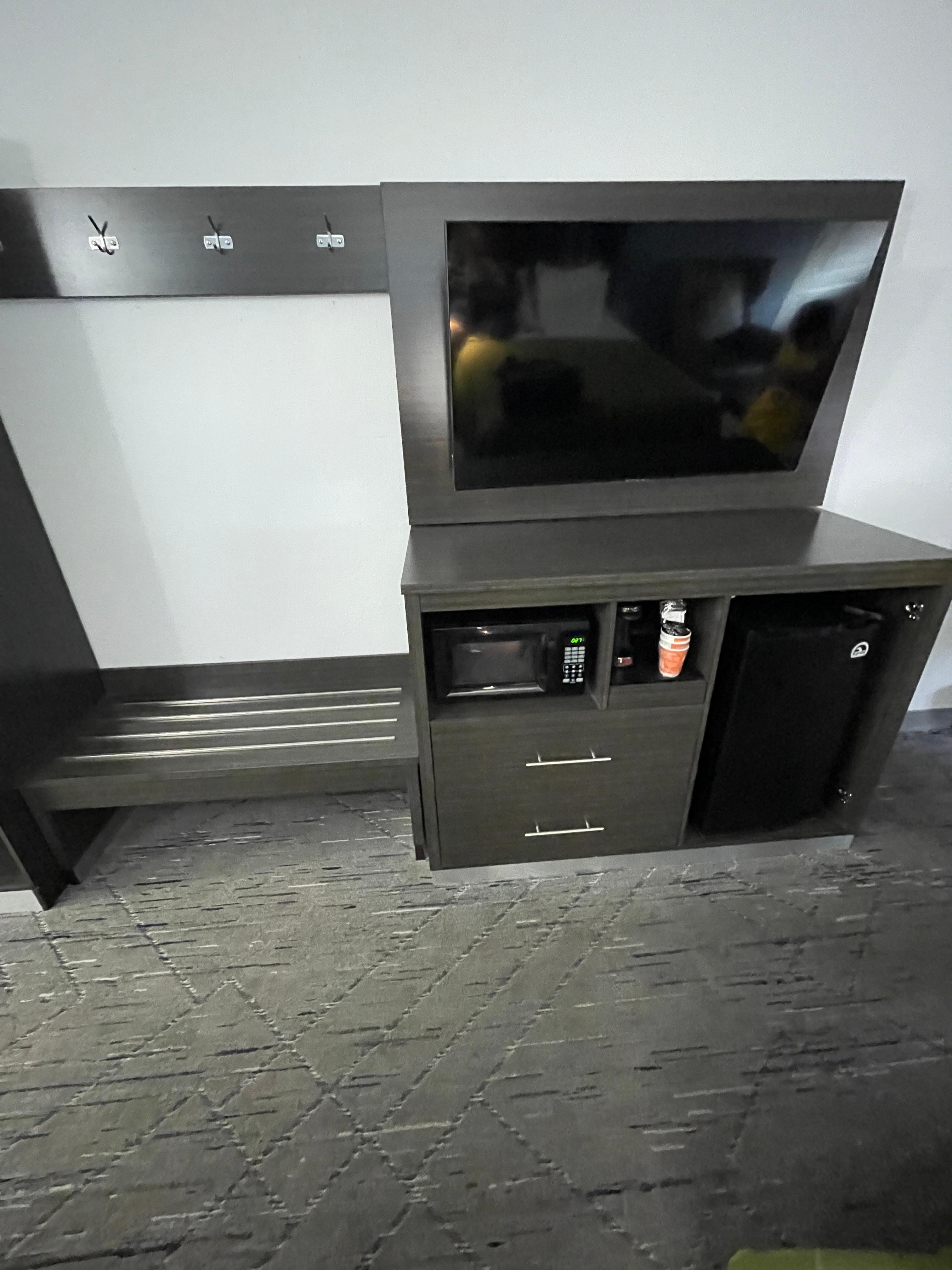 Tv and plant of storage for anything you might need to put away with a microwave coffee maker and fridge 