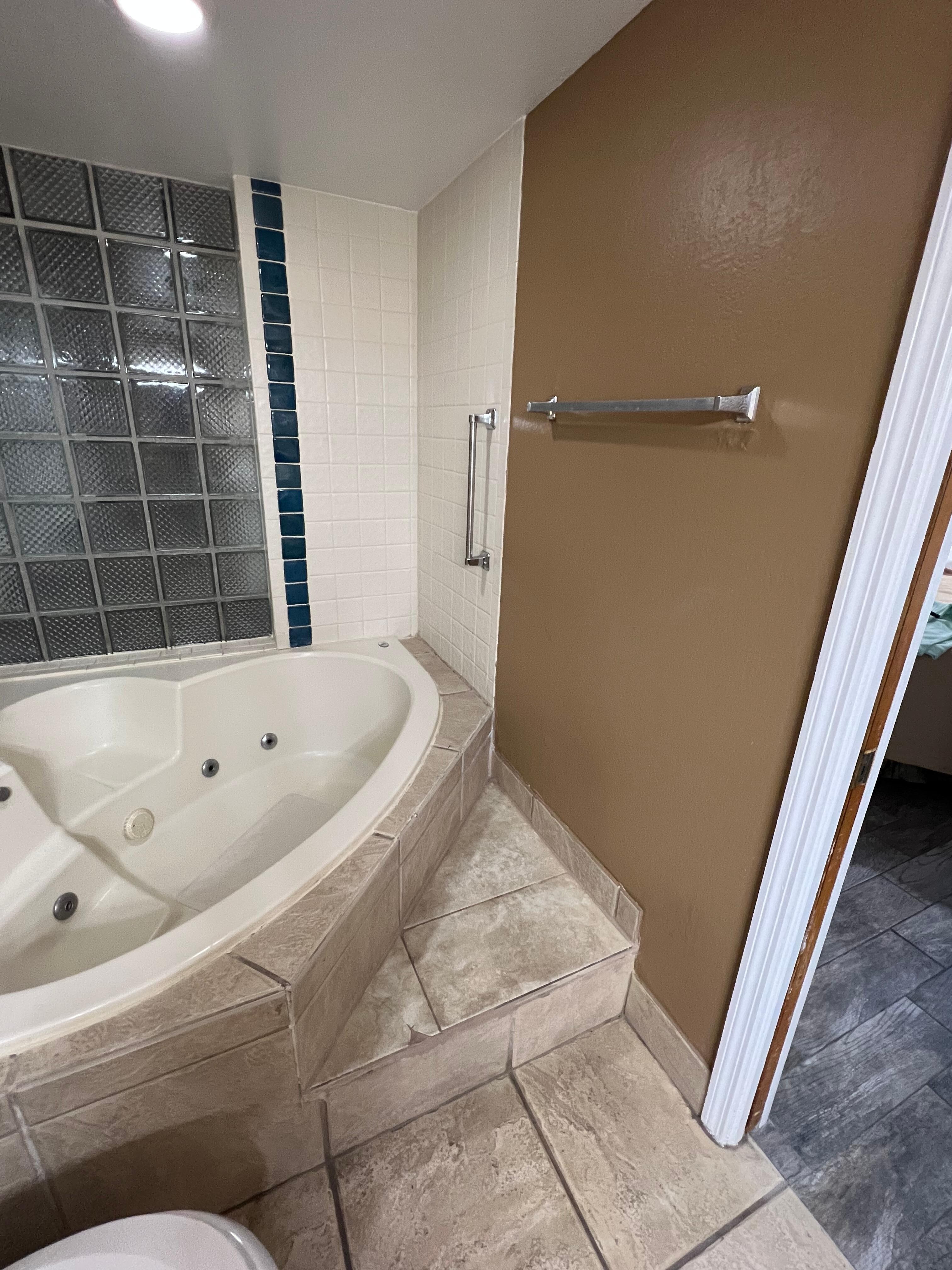 Steps to climb to get Into the primary shower/ tub. The handicap handrail is so far back the towel rack looks as if it has been ripped off a time or two and poorly patched back up on the wall. 