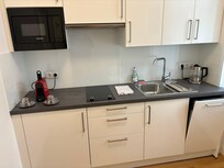 キッチン。電子レンジ、電熱調理器、冷蔵庫、食洗機、ポット、ネスカフェなどがあった。