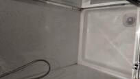 Bottom of shower stall, bathroom extremely small.