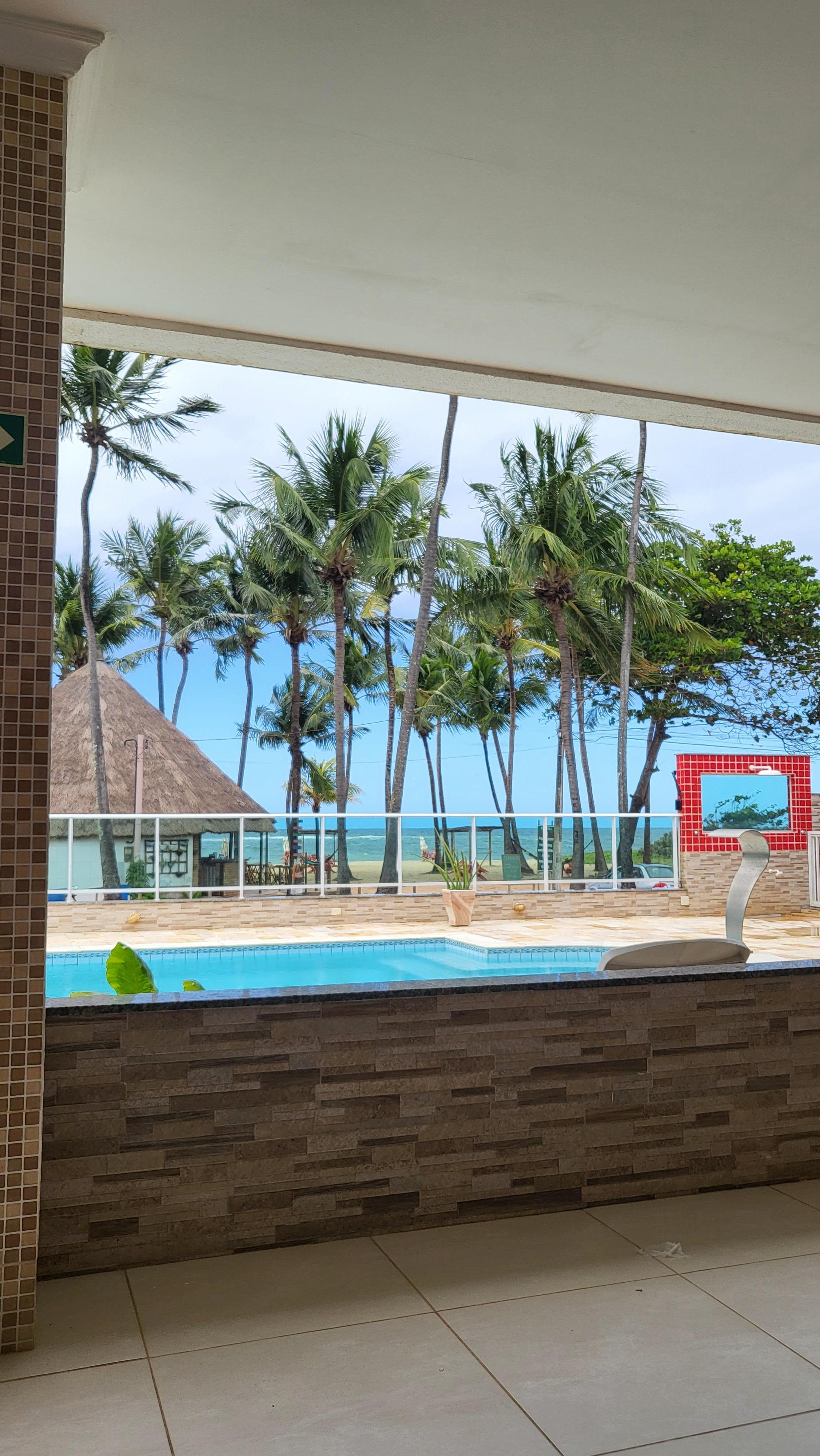 Varanda comum coberta com vista da piscina e do mar.