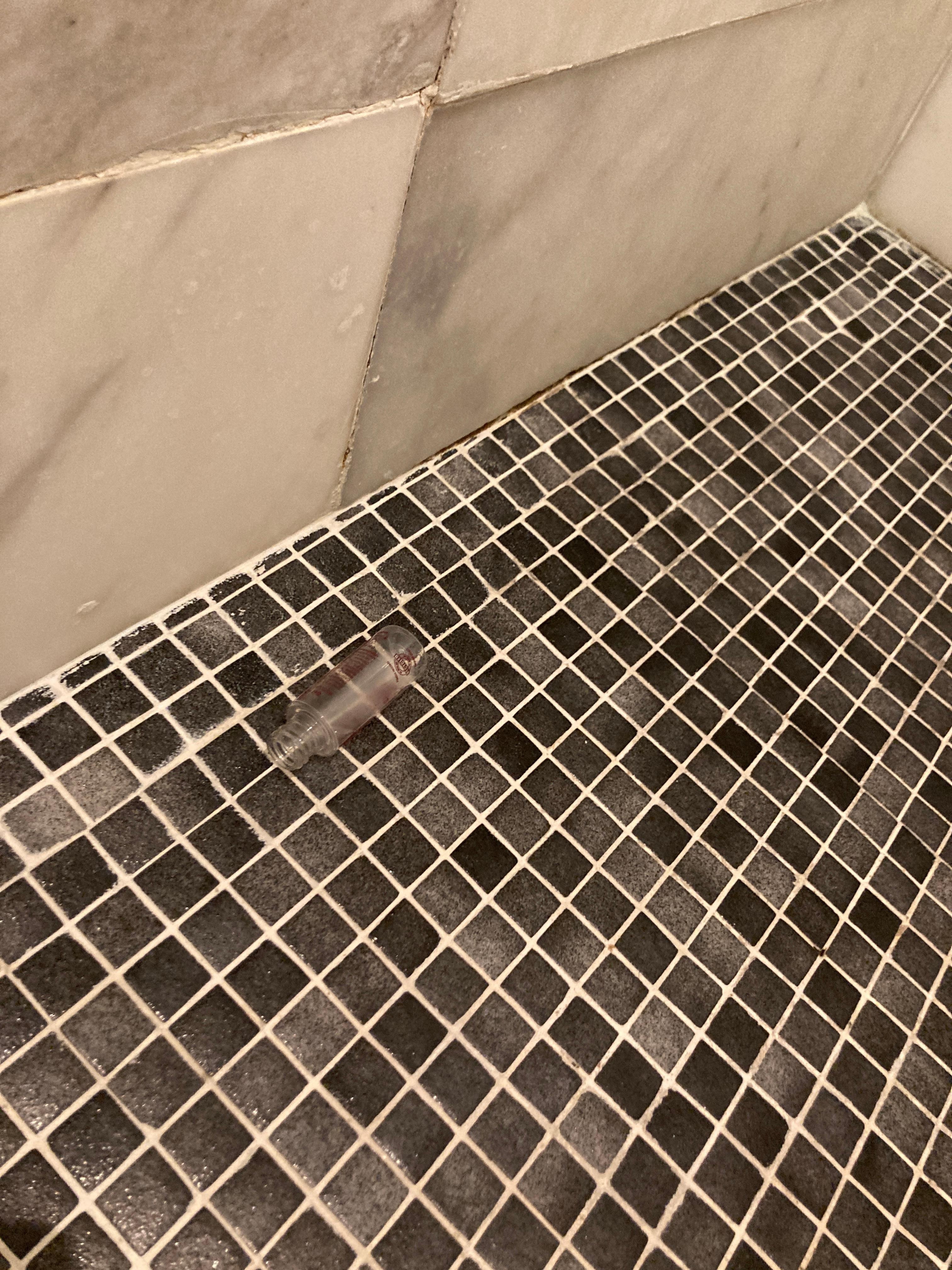 Old and emptly shampoo bottle on the floor from previous guest