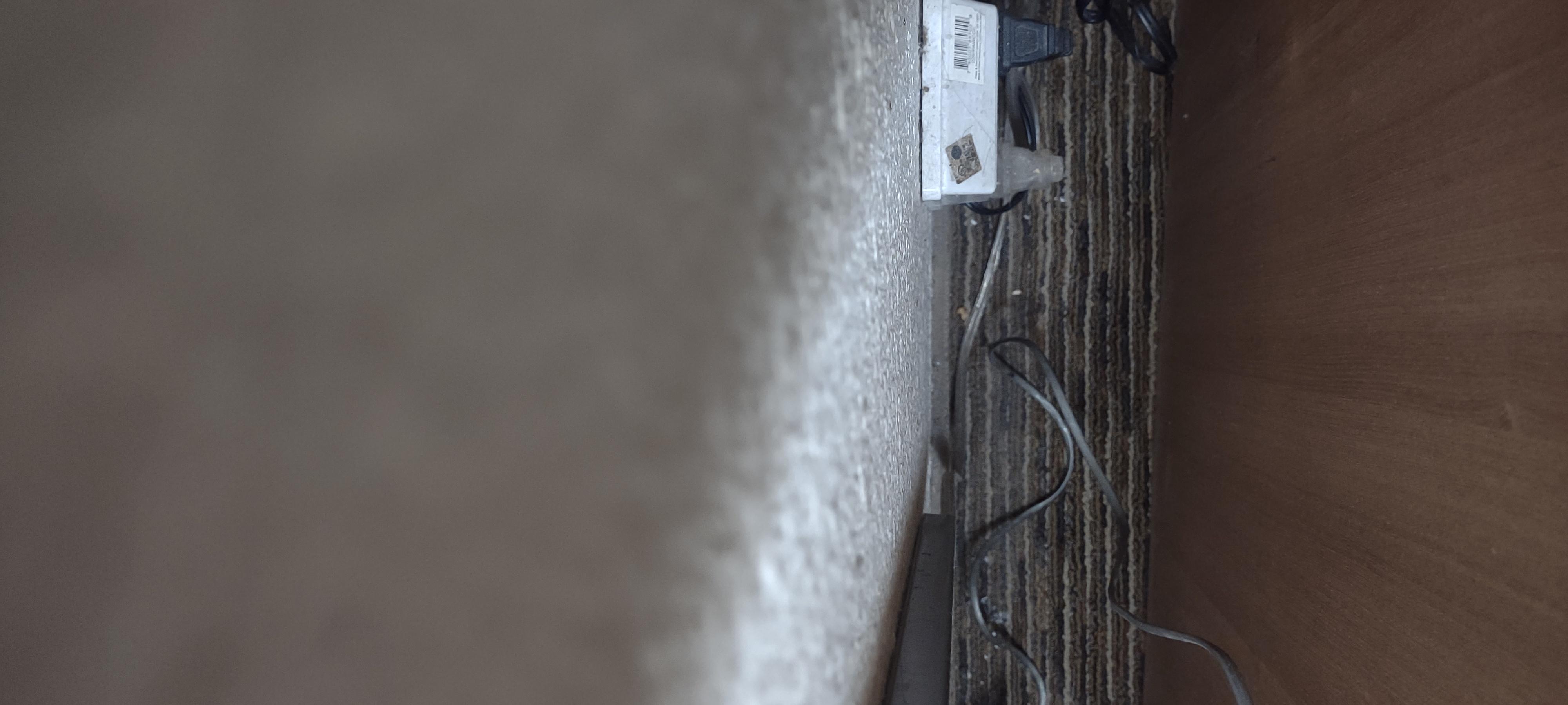 Behind the bedside table.  Had to move it to get to the outlet with a multi plug, (safety? And dusty) not cleaned recently carpet dusty