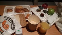 Café da manhã oferecido para viagem antes do horário da abertura do restaurante. Café com leite, suco de laranja, diversos tipos de pães e croassants, frutas, geléia, mel e manteiga.