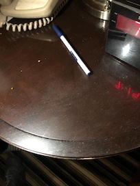 Mesa de noche , sucia y donde aparenta haberse derramado una bebida , ademas de sucia esta pegajosa