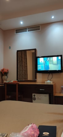 Taken from right side of bed, has a desk, mirror, mini fridge beneath, tv above, to far left is a round table and 2 chairs, night stands have nice drawers