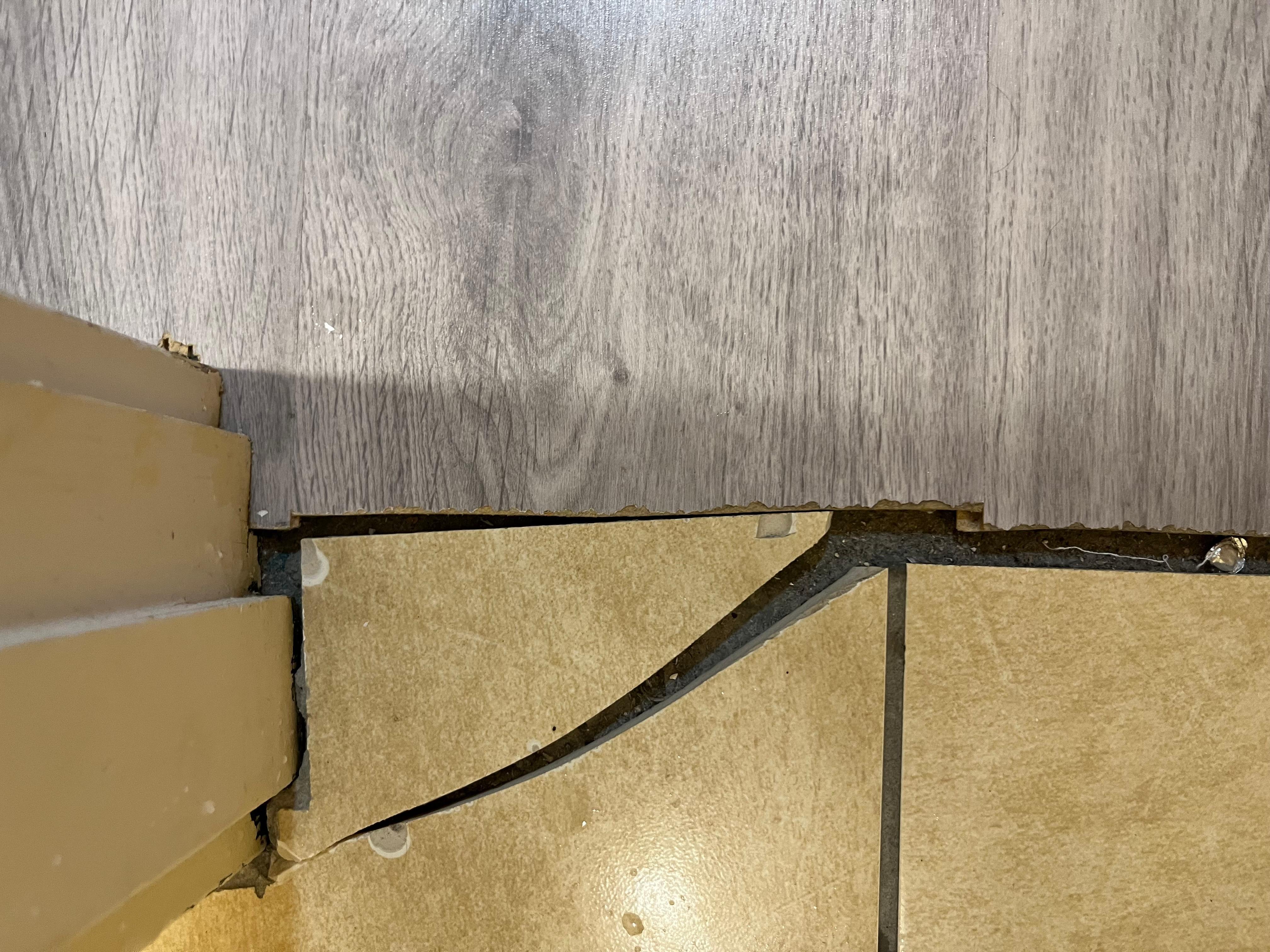 Broken tile and gap in flooring at bathroom door