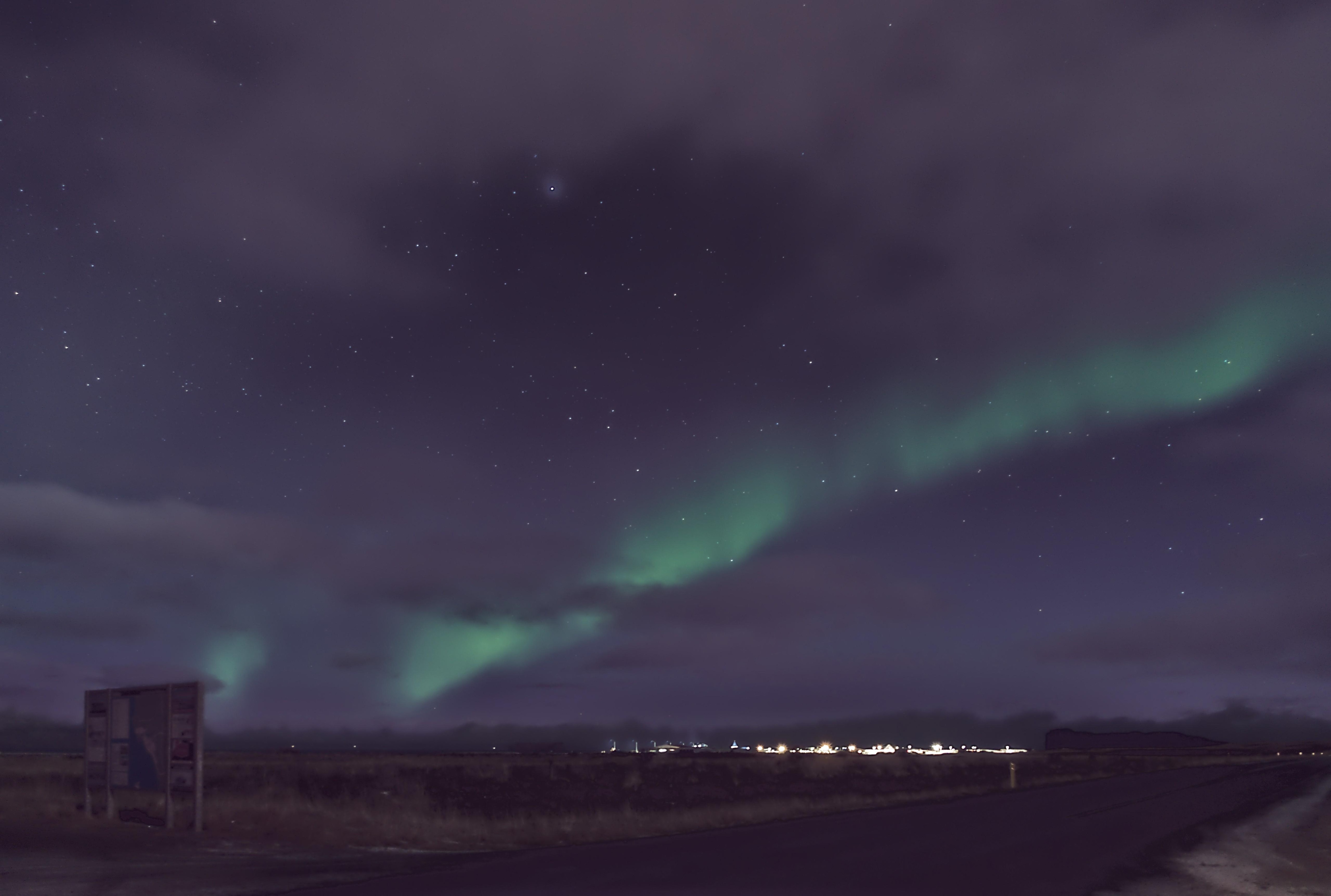 Northern Lights over Hofsós on a moonlit, partly cloudy night