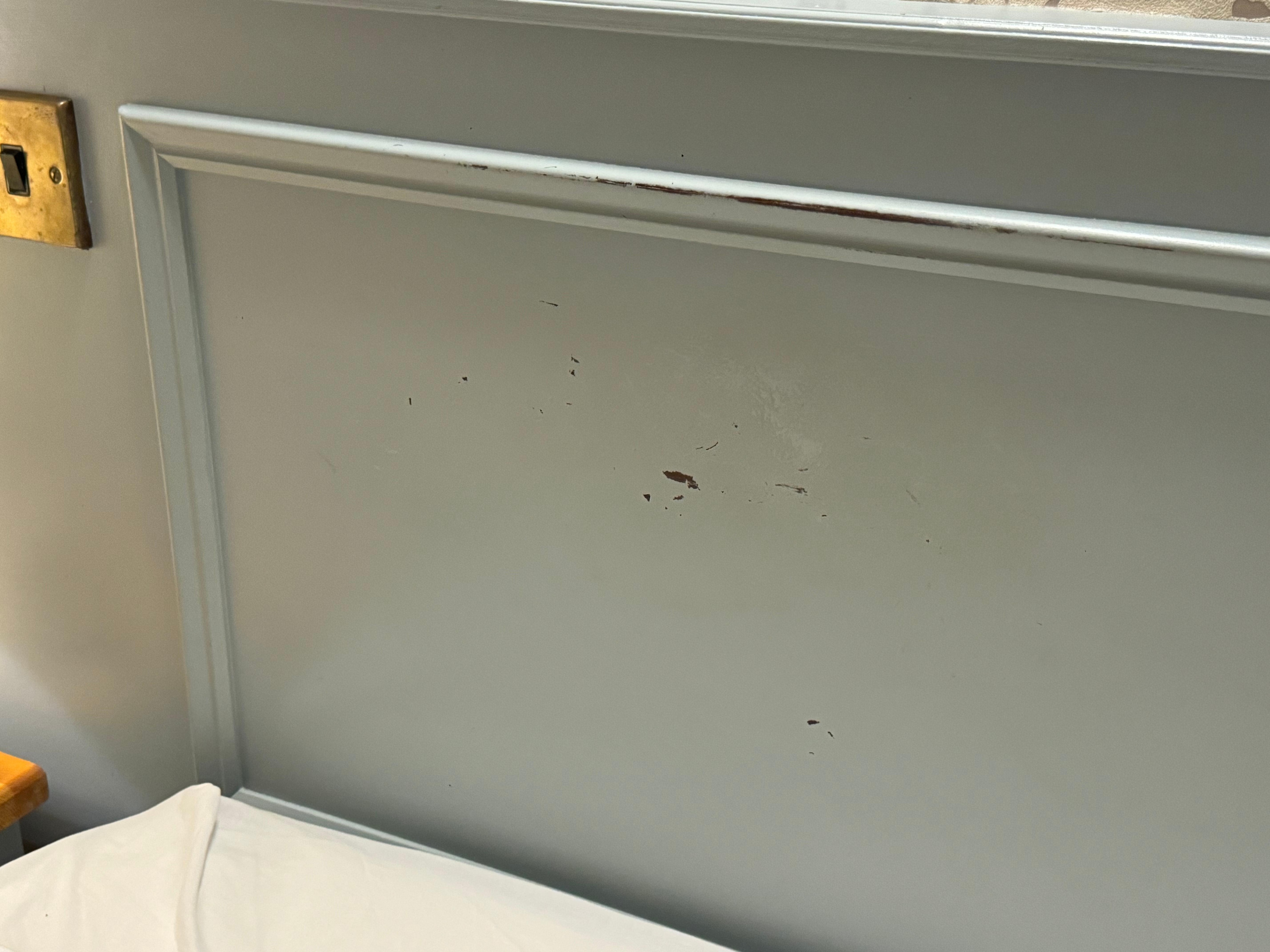 Scraped off paint on headboard /wall.