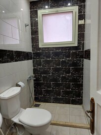 Bathroom- broken wall attachment- no shower curtain or bathmat.