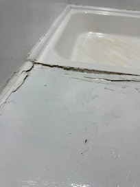 Shower with cracks, mildew, used shampoos, moldy shower curtain.