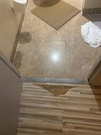Le sol est dégradé en entrant dans la salle de bains et pas réparé. Il n'y a pas de tapis de bain pour le sol mais une grille en plastique idéale pour attraper des mycoses.