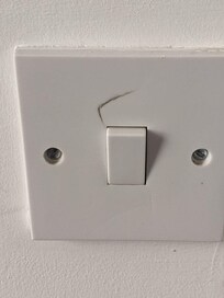 It appears that someone pushed the light switch too hard. The Crack appears to go fully through the plastic.