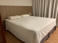 A bed with no duvet or blanket in a room with no heating