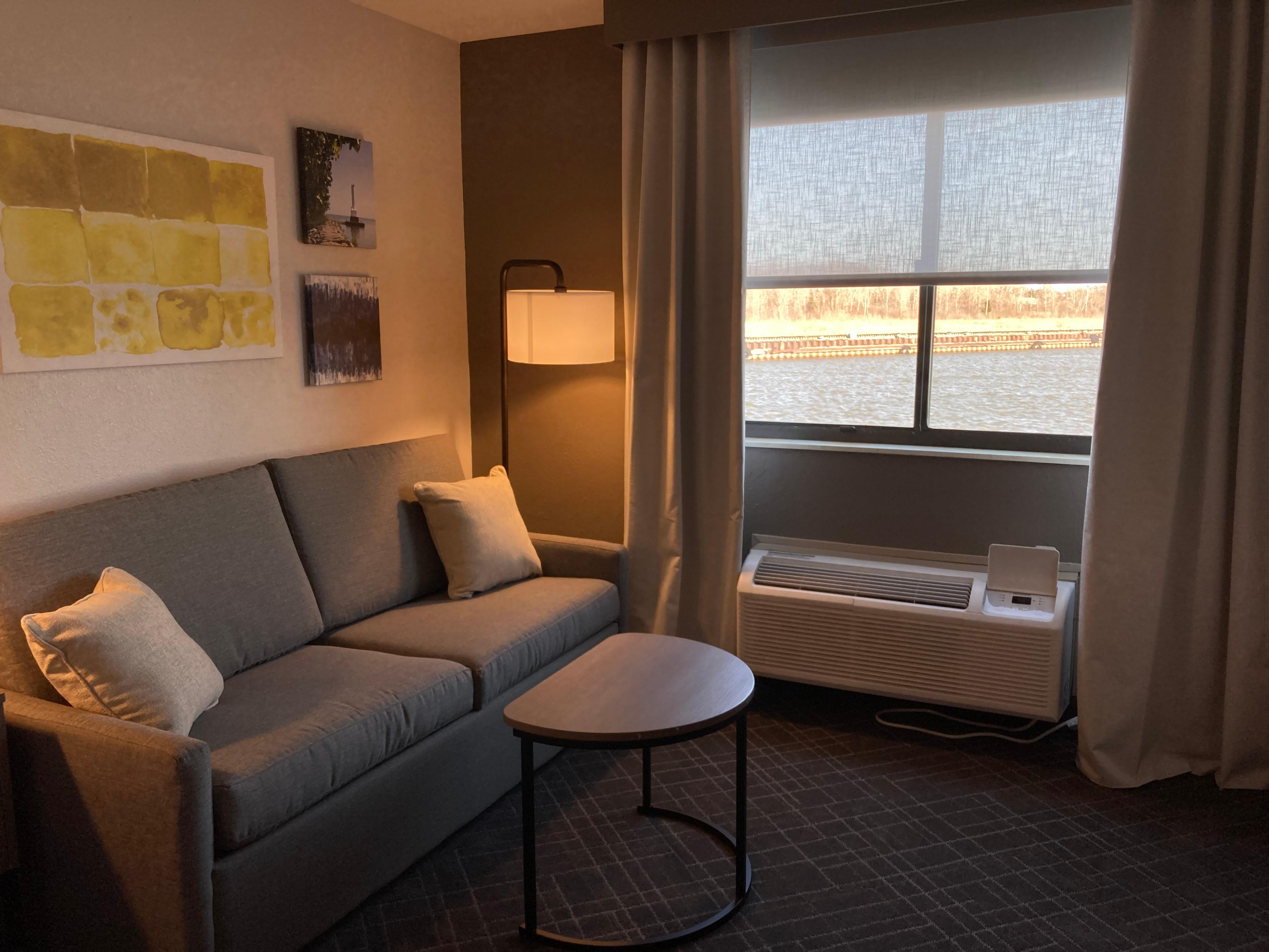 Cozy little couch with a little table for reading and a cute lamp for some light next to a nice view of the lake.