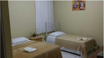 Foto do quarto 12 no site da Pousada, atrás da cama de solteiro tem 2 degraus de acesso a porta trancada atrás da cortina.