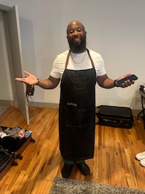 Husband wearing their apron. He found it in the drawer and was so happy he didnât have to dirty his white shirt.