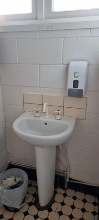 Antiquated, old and dirty sink and bathroom tiles.