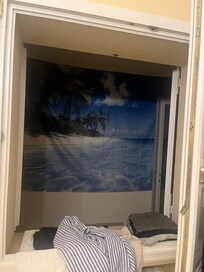 Drap de plage derriĂšre la fenĂȘtre de la chambre en guise de cache misĂšre