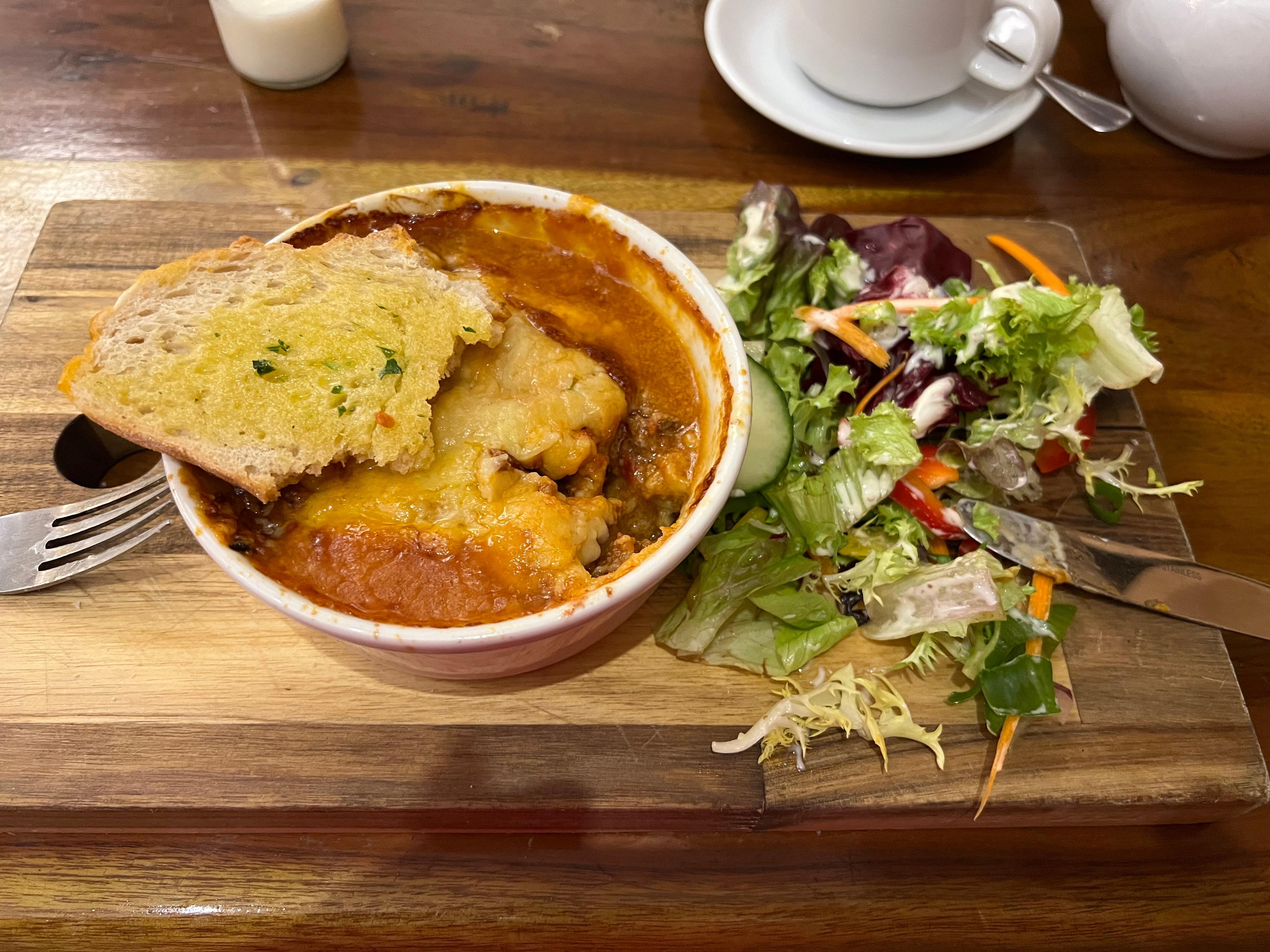 Lasagne, garlic bread and side salad, served on a wooden platter