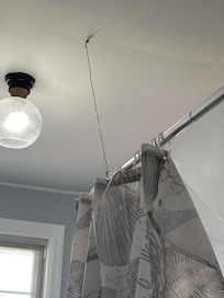 Shower rod was attached by a crude wire bolted into the ceiling