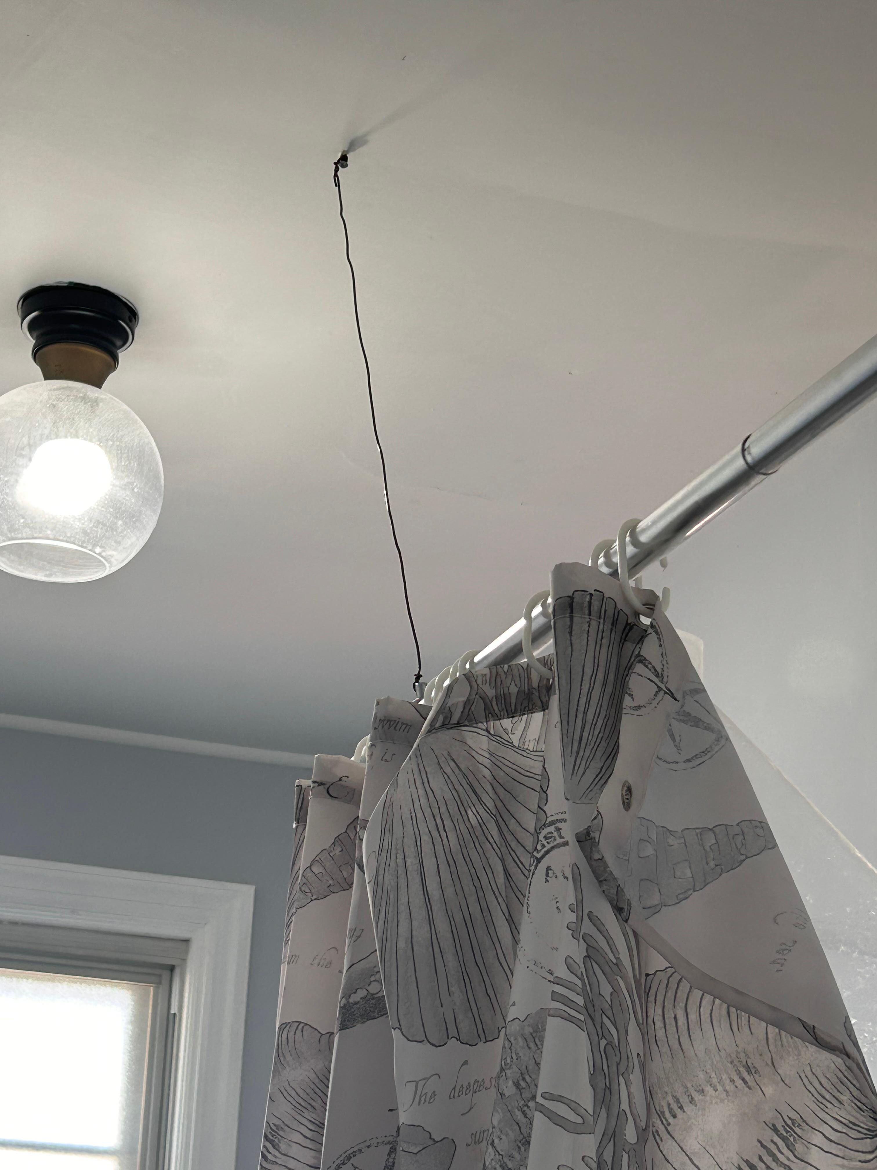 Shower rod was attached by a crude wire bolted into the ceiling
