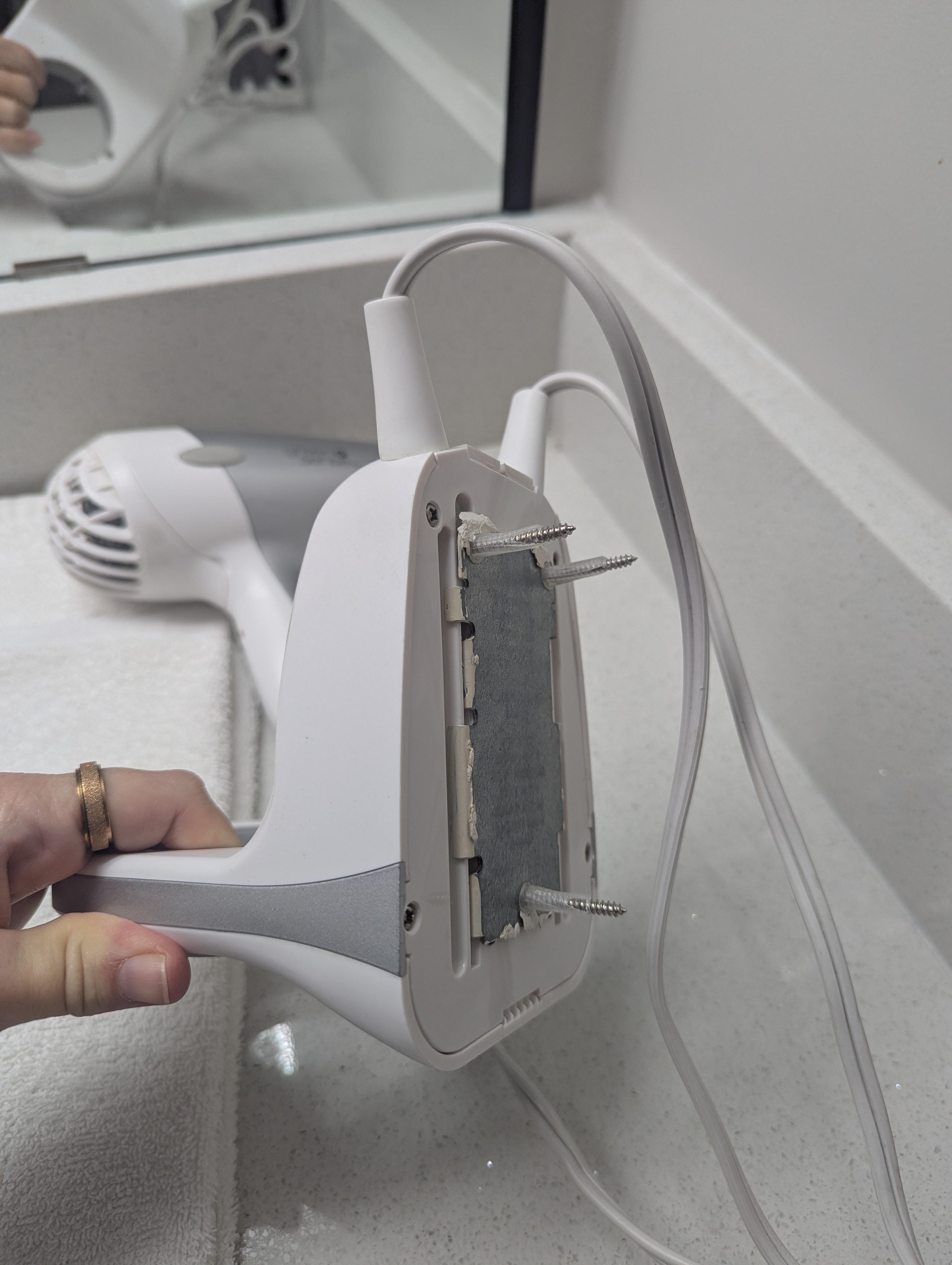 Hair dryer holder just lying on counter with the dryer, has screws but I guess the forgot to reinstall it after painting? 