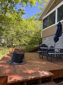 Deck facing the lake equipped with seating, fire pit, and gas grill