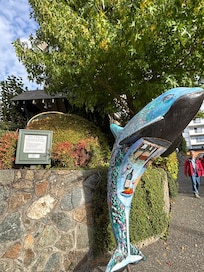 The unique sculpture at the entrance is surrounded by well kept shrubbery and blooming plants.