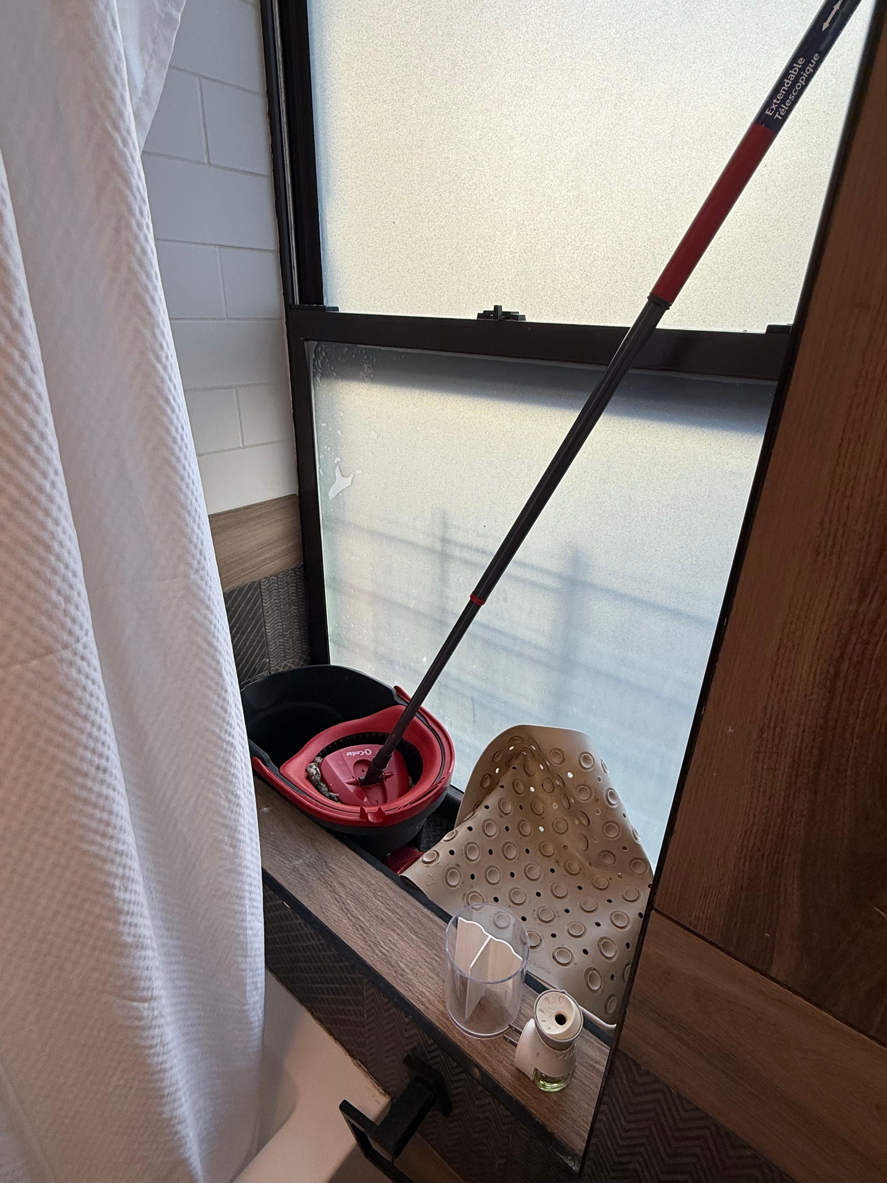Filthy mop, bucket and bathtub mat shoved in the windowsill