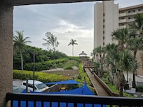 View severely limited by beach-front building, raised pavillion, and trees.