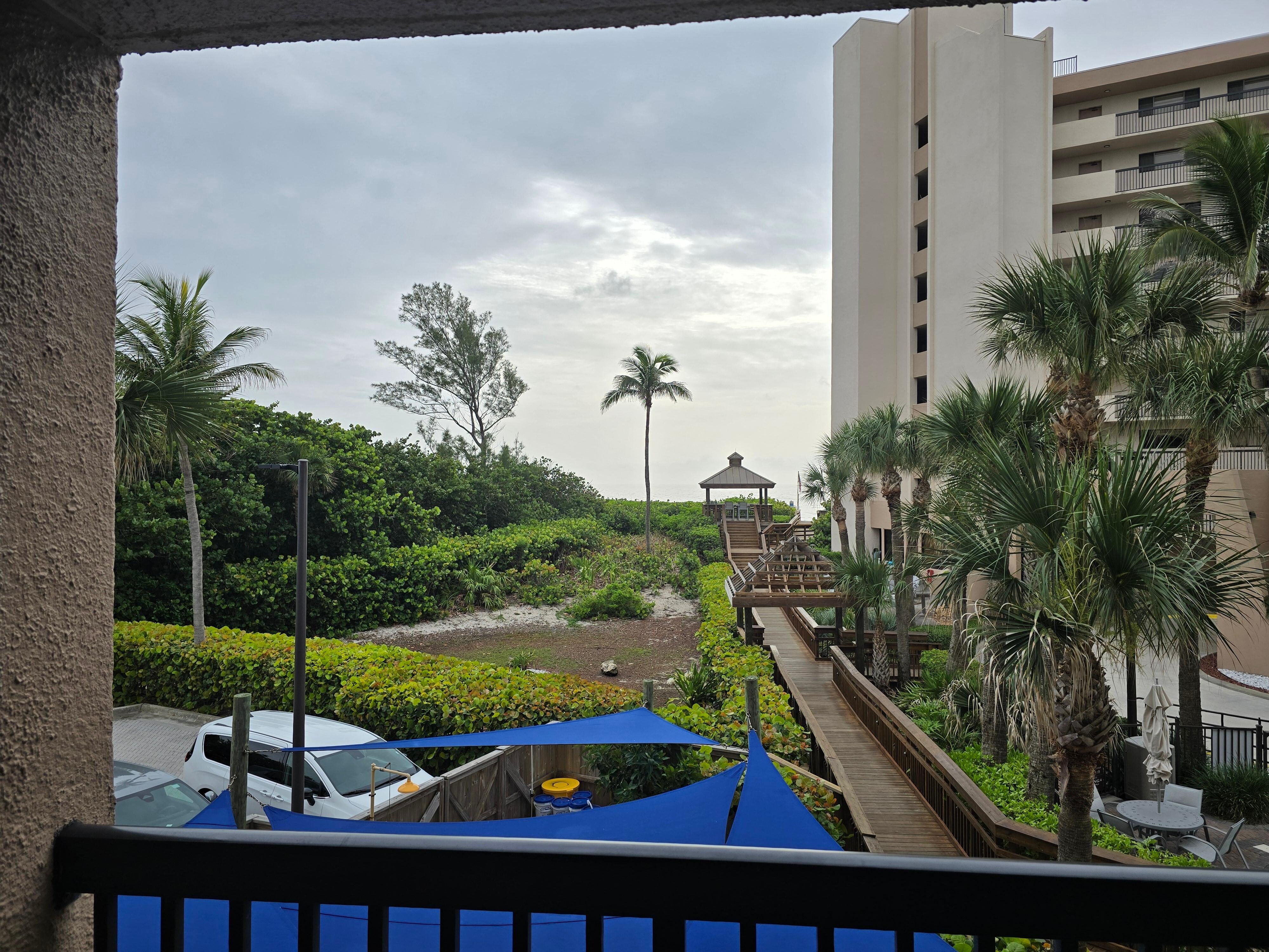 View severely limited by beach-front building, raised pavillion, and trees.