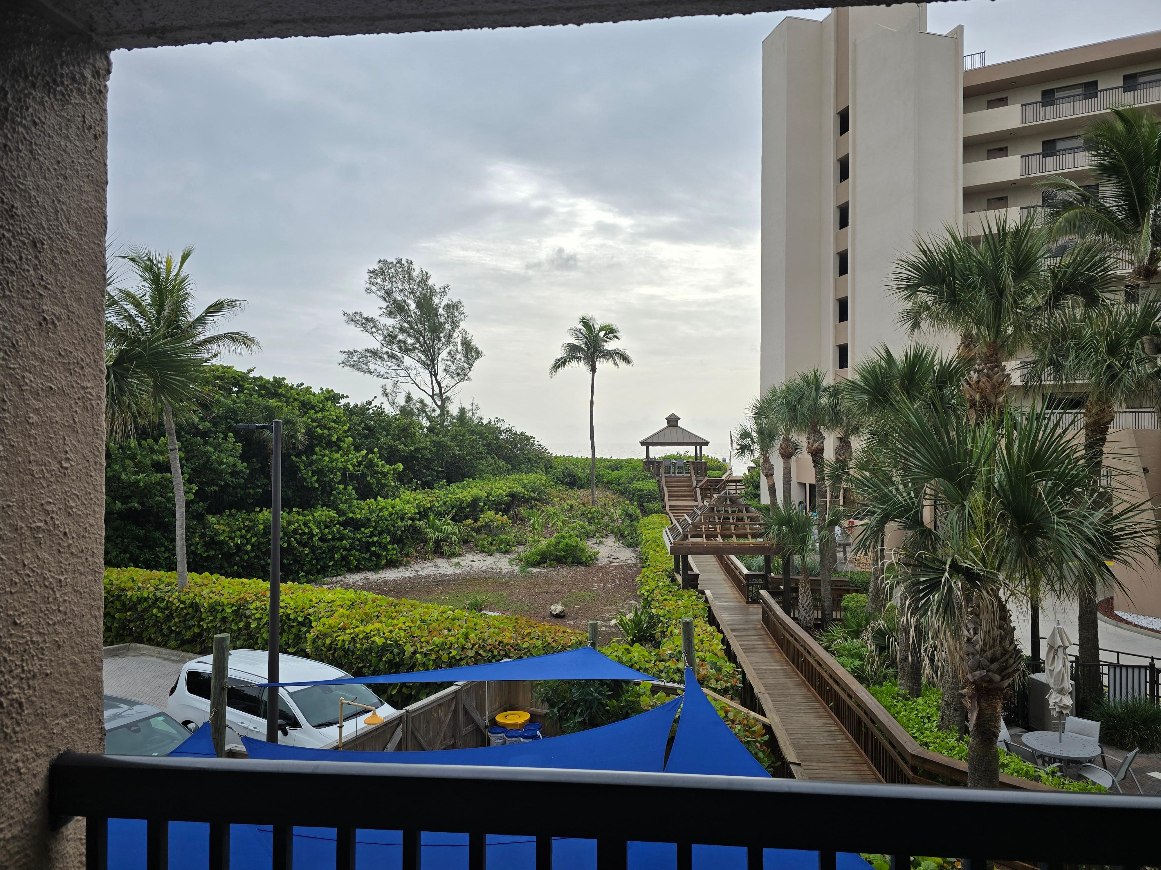 View severely limited by beach-front building, raised pavillion, and trees.