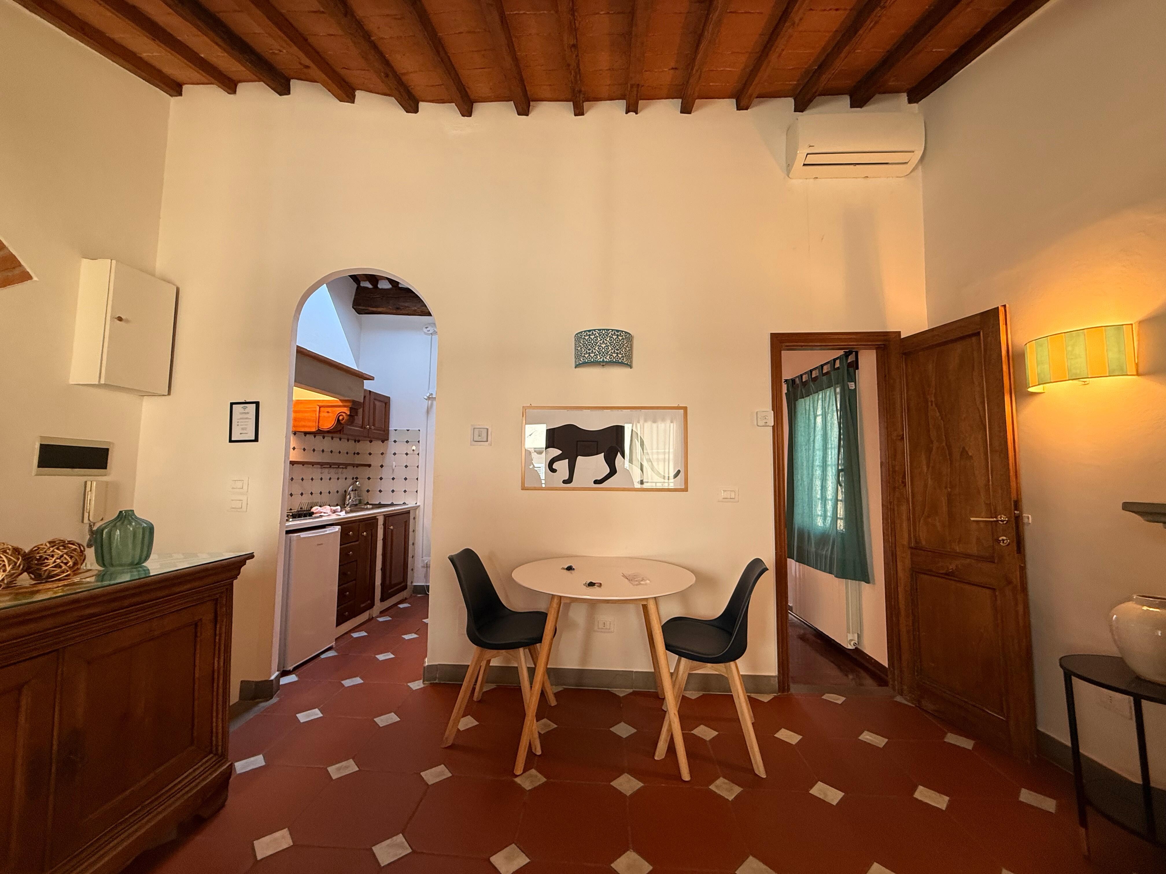 cute living space with a nice little kitchen, a few seating options, and windows on two sides of the apartment