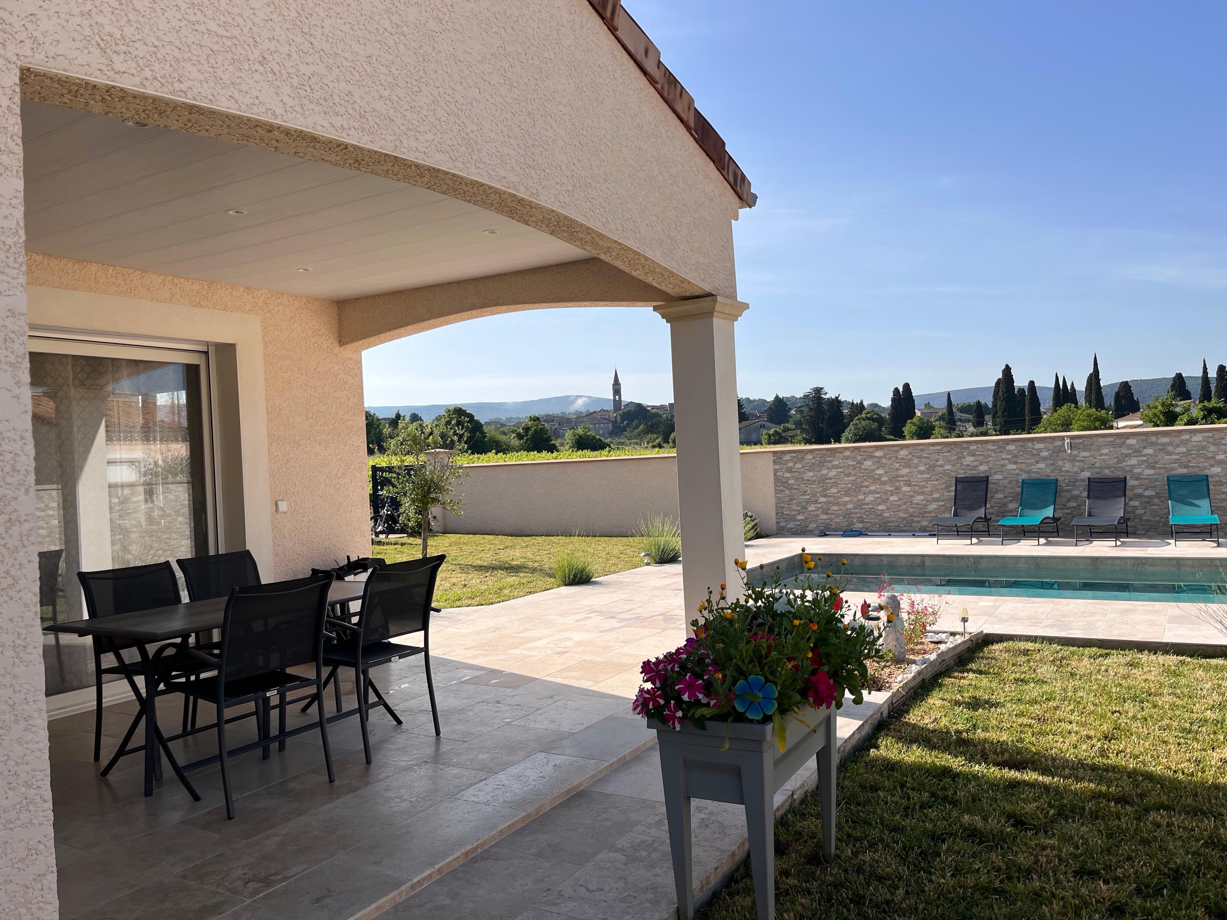Vue de la pergola sur la piscine et derrière le mur les vignes 