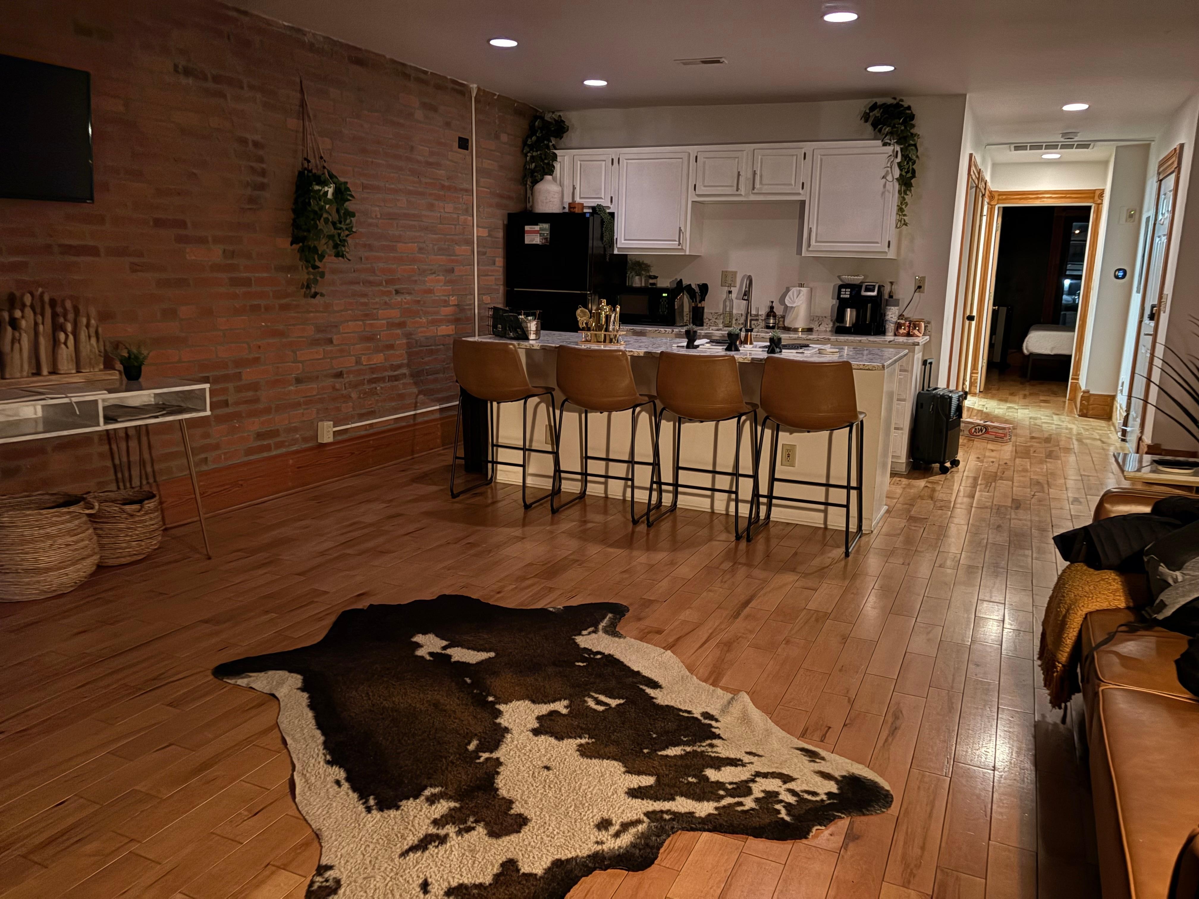Standing against the jungle plants and the street-side windows, looking into the kitchen.