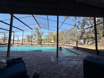 Huge covered pool area with lounge chairs, table and chairs, and a patio box with pool floats/goggles and sand toys for the beach
