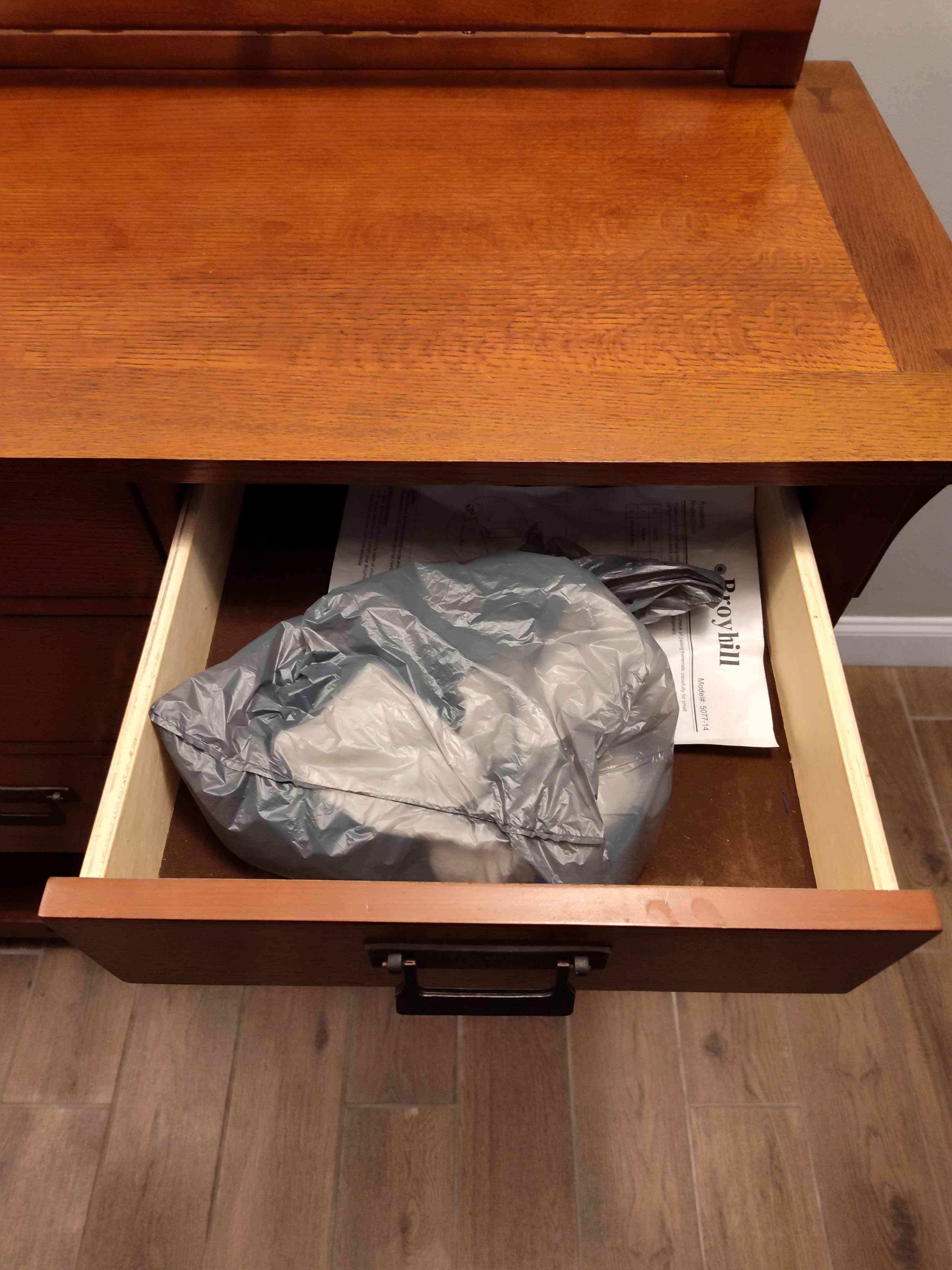 Grocery bag in a drawer of the living room credenza with a pair of socks and another unidentified article of clothing.
