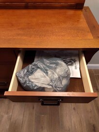 Grocery bag in a drawer of the living room credenza with a pair of socks and another unidentified article of clothing.