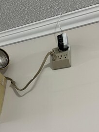 Emergency light has random cord plugged into extension cord. Drilled in through wall.