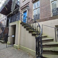 The open gated door is the entrance. Common for steps and buildings to be green and moss or fern covered in Savannah. Adds to the city charm