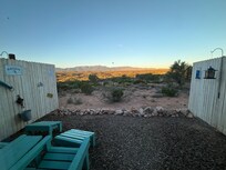 Fenced yard with 2 Adirondack chairs.