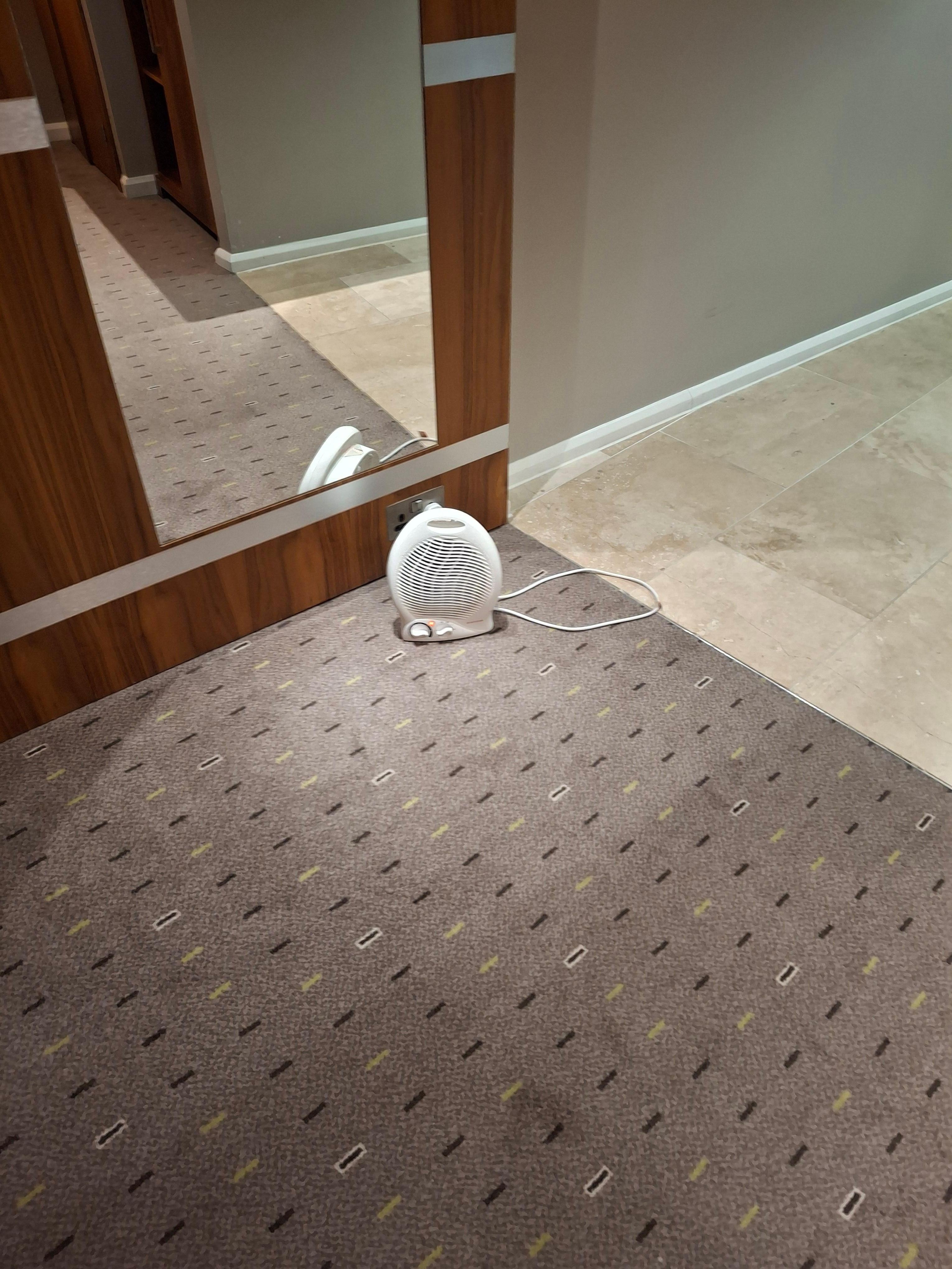 The heater is plugged down on the floor like a prisoner 