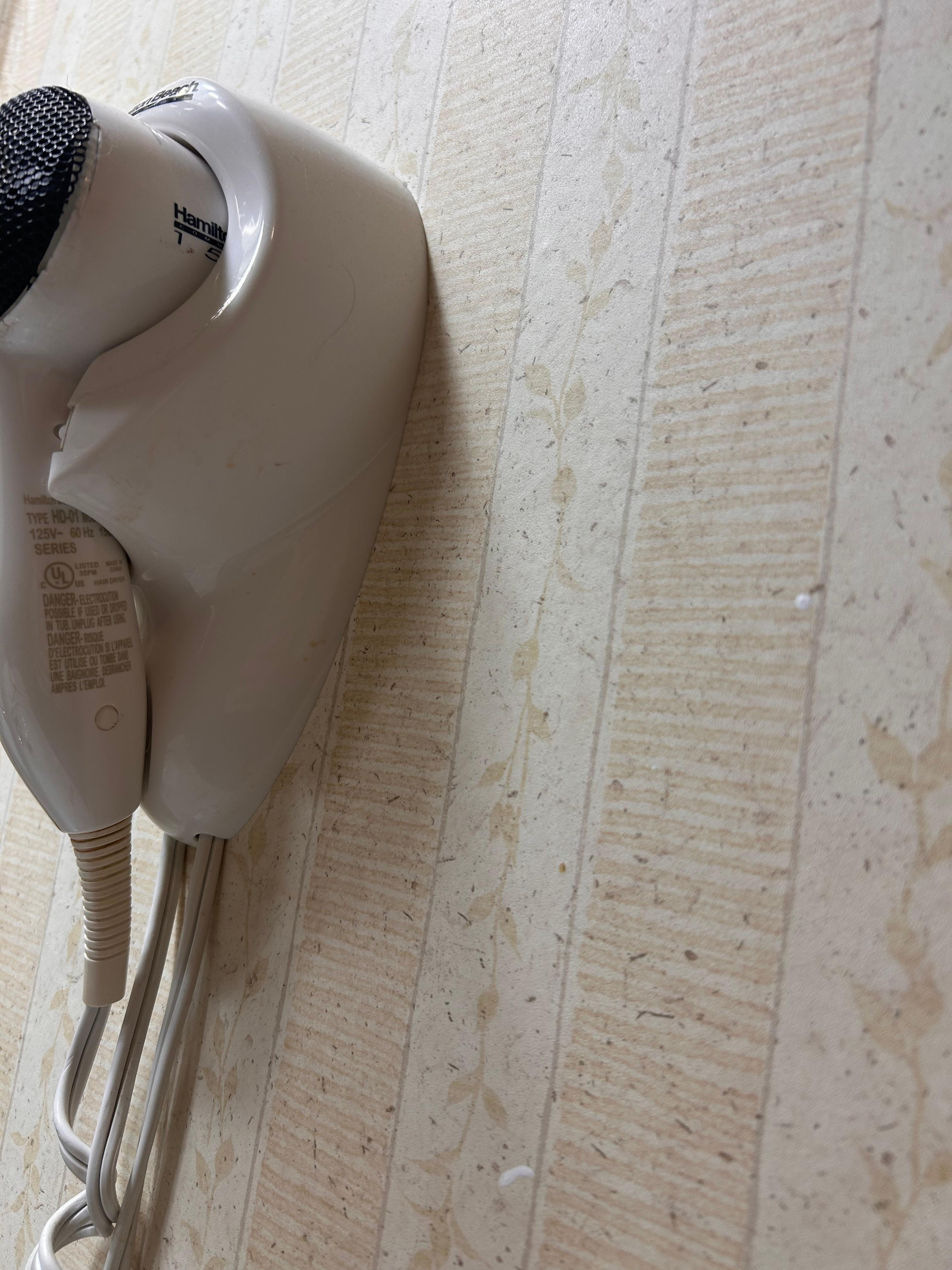 Orange drip marks on hair dryer and toothpaste splatter on wall