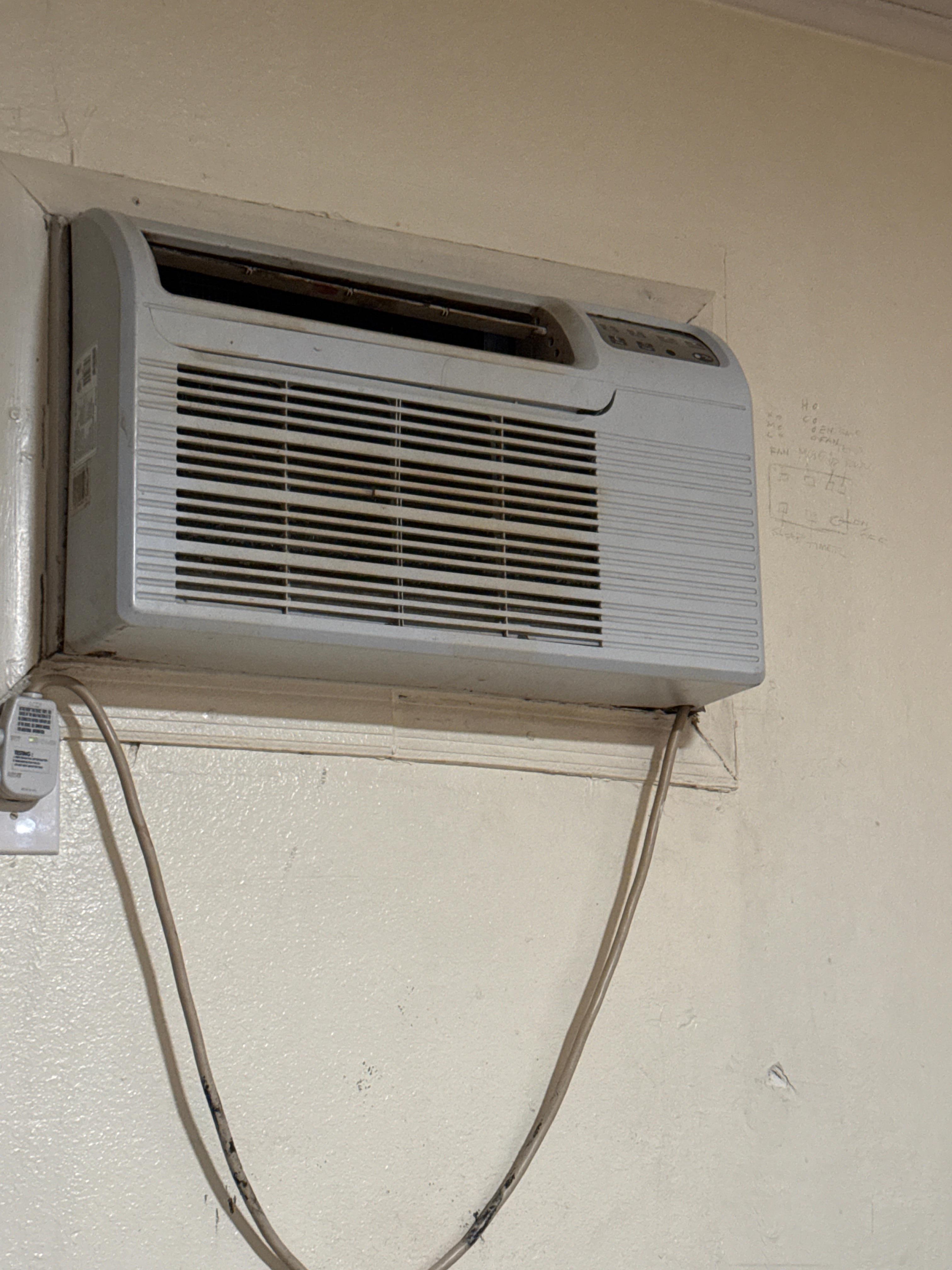 Broken and filthy AC with control panel written on the wall