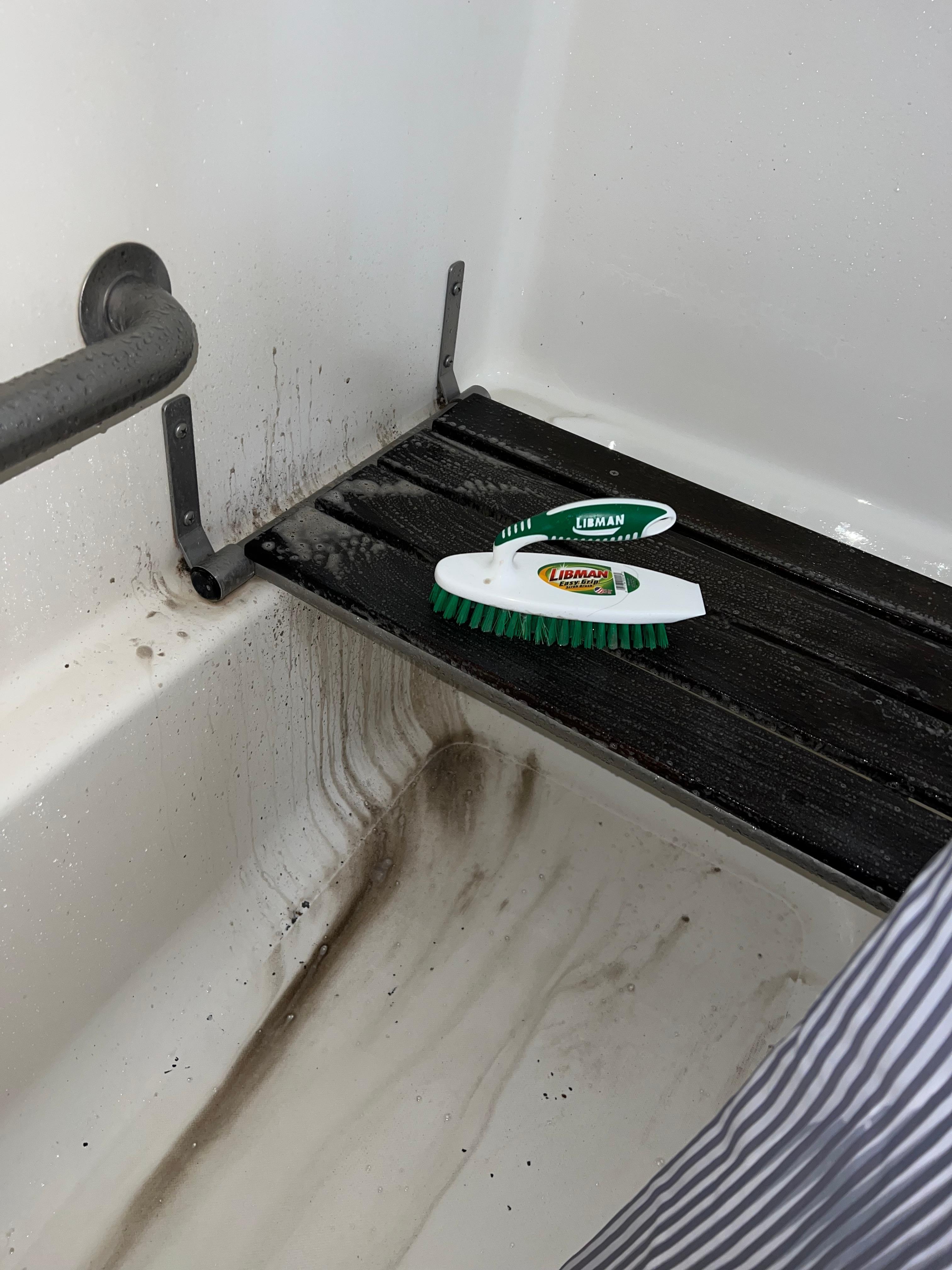Scrubbing caked up fecal matter from the shower disability seat.