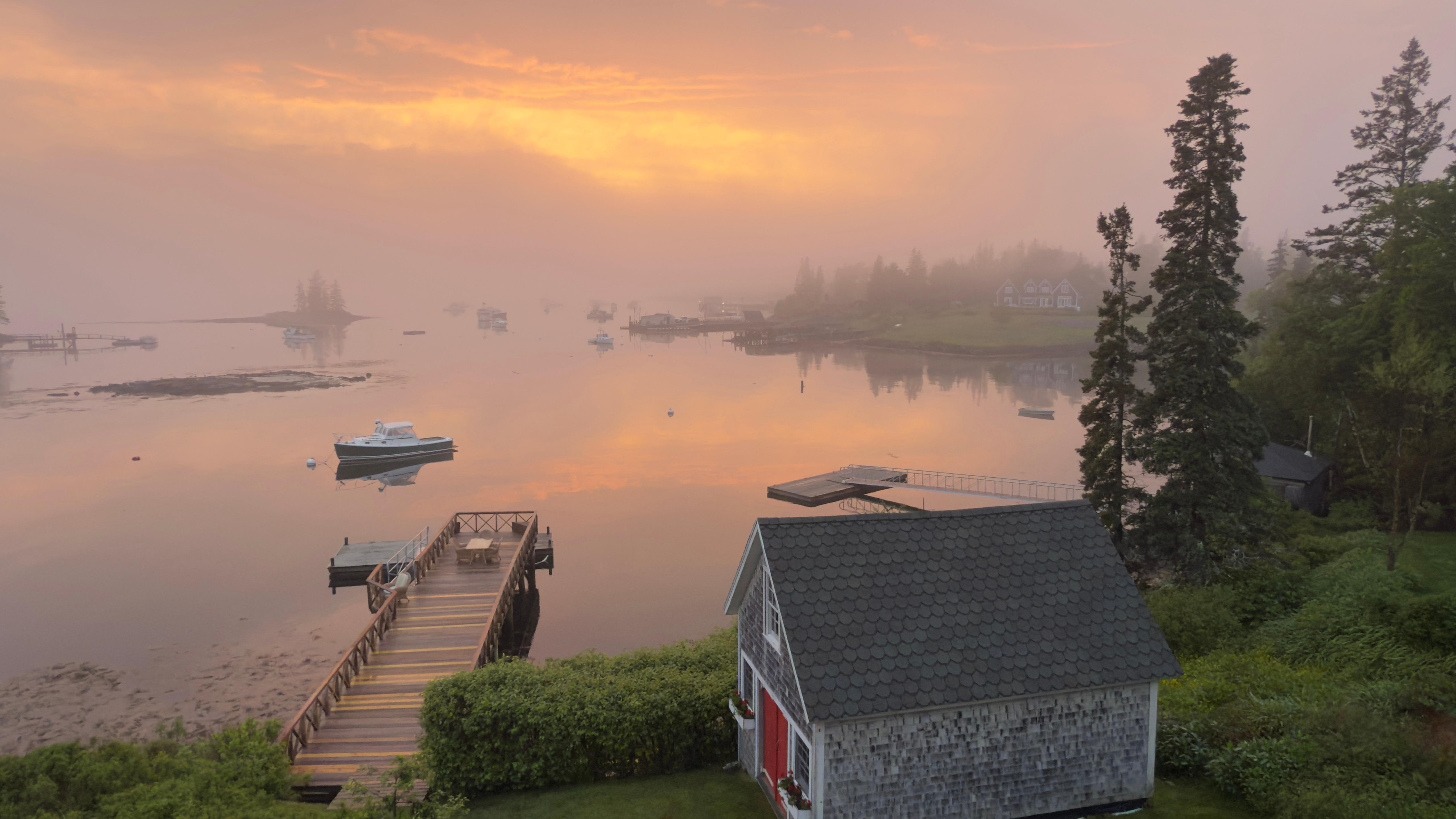 Boathouse and dock during a foggy, drizzly sunset.