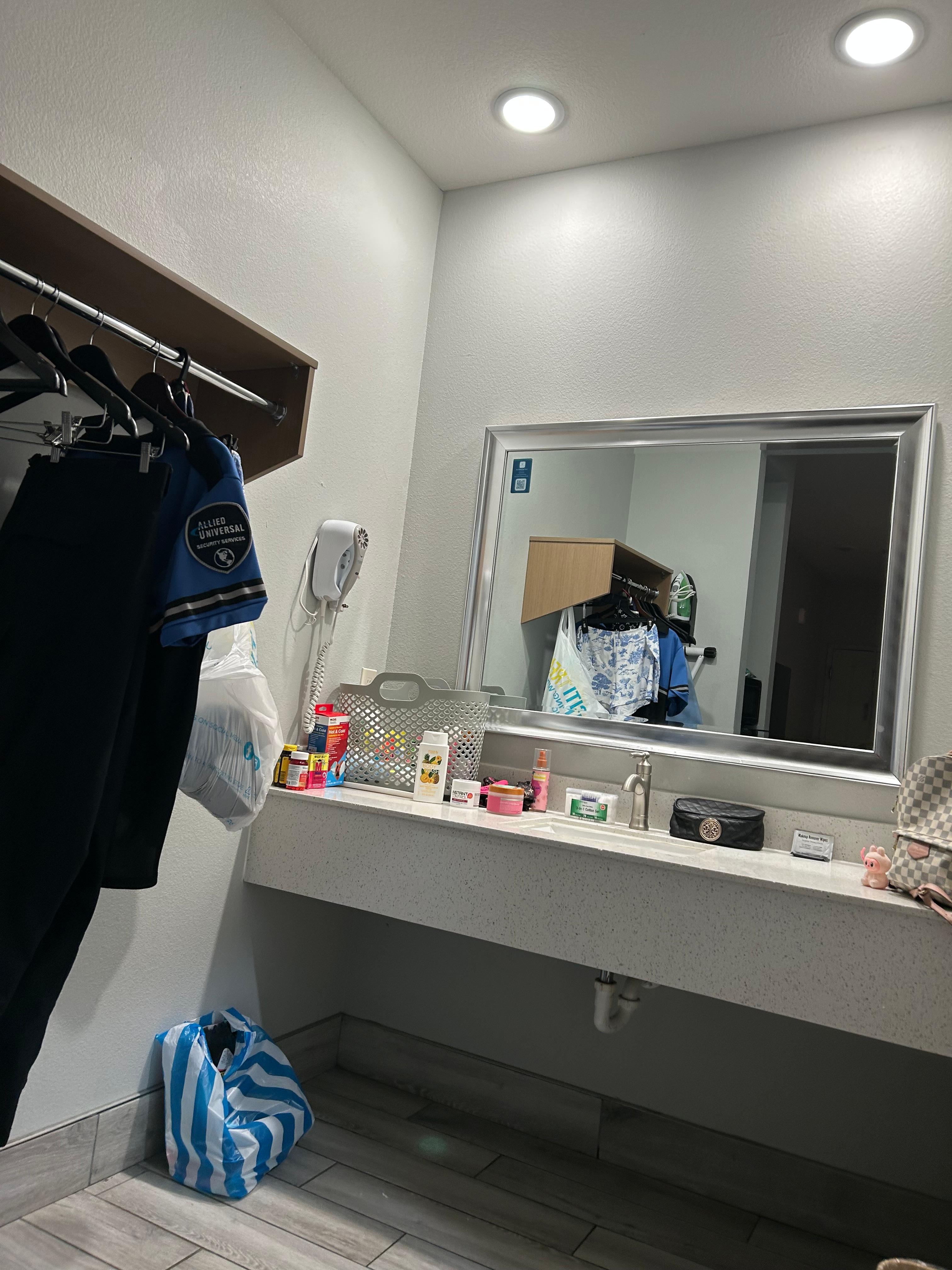 The sink area/closet area with a iron board, hairdryer and iron