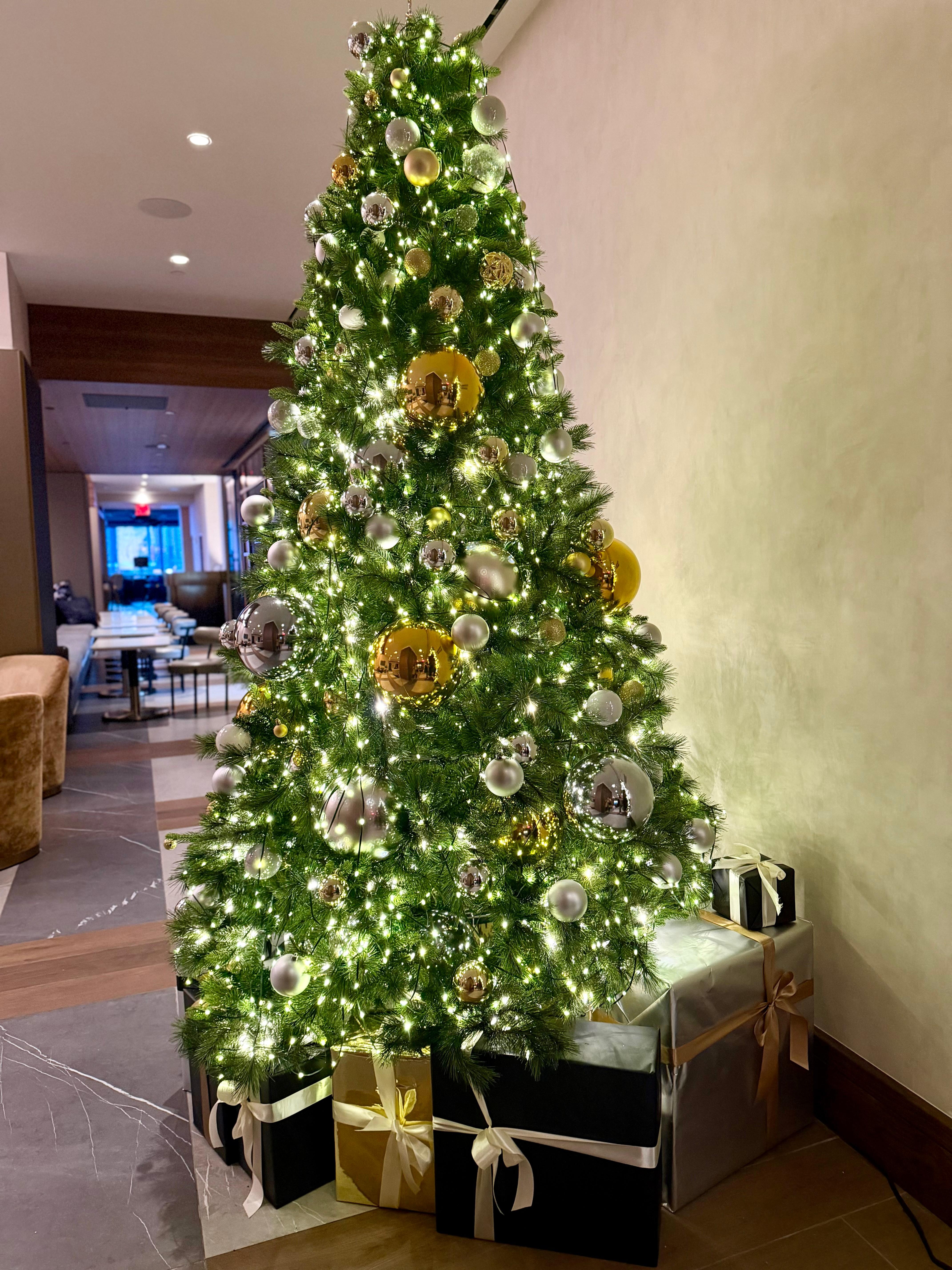 Christmas tree in lobby area by restaurant and elevator. 