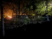 Back view of cottage from fire pit with deck lights on the left